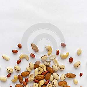 Assorted roasted and raw nuts scattered on white