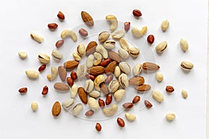 Assorted roasted and raw nuts scattered on white