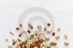 Assorted roasted and raw nuts scattered on white