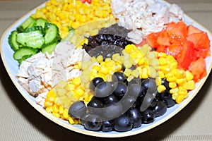 Assorted salad with olives on a plate. Ingredients: chicken meat