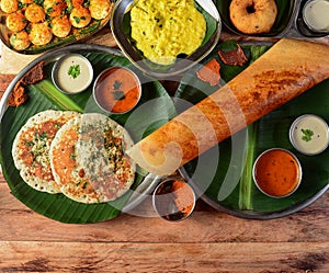 Assorted South indian breakfast foods on wooden background. Ghee dosa, uttappam,medhu vada,pongal,podi idly and chutney.. Dishes