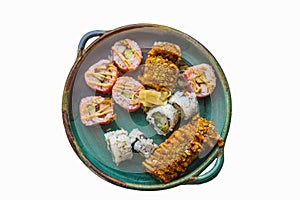 Assorted store bought sushi rolls with some ginger on a rustic platter isolated on white