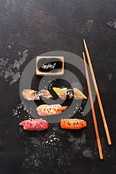 Assorted sushi set on a black stone background. Japanese food sushi, soy sauce, chopsticks. Top view, copy space