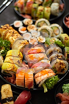 Assorted sushi set served on dark dark background. Top view of seafood, various maki rolls