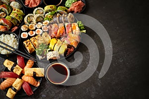 Assorted sushi set served on dark dark background. Top view of seafood, various maki rolls