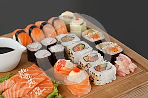 Assorted sushi set served on wooden tray against black background