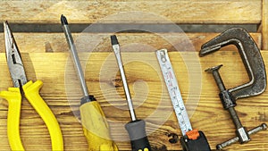 Assorted tools aranged on a wooden bench in yellow color