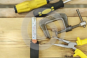 Assorted tools aranged on a wooden bench in yellow color