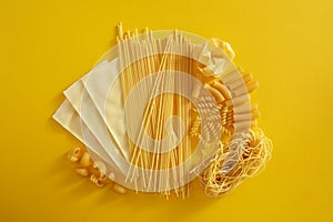 Assorted types of pasta on yellow background.