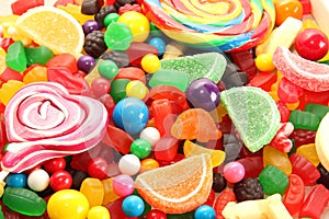 Assorted variety of sweet sugar candies includes lollipops, gummy bears, gum balls and sugar fruit slices