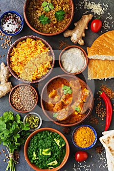 Assorted various Indian food on a dark rustic background. Traditional Indian dishes - Chicken tikka masala, palak paneer, saffron