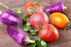 Assorted vegetable with purple exotic color bell peppers and tomatoes isolated on stone background.