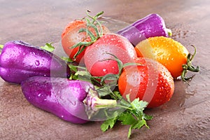 Assorted vegetable with purple exotic color bell peppers and tomatoes on stone background.