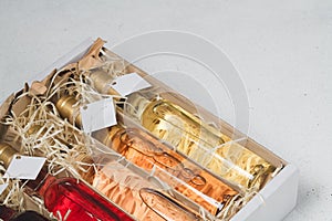 Assortment of 250 ml bottles of red, pink, white wine in box of wooden shavings, no label. Set of alcohol drinks for present or