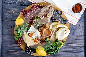 Assortment of appetizer: grapes, cheese, blue cheese, figs, melon, arugula, grain bread, honey