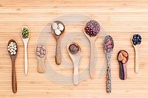 Assortment of beans and lentils in wooden spoon set up on wooden