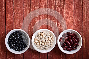 Assortment of beans in white bowl on rustic wood