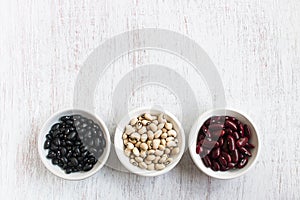 Assortment of beans in white bowl on rustic wood