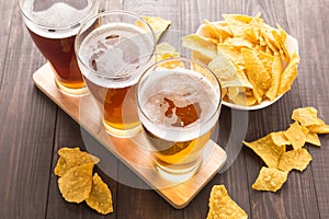 Assortment of beer glasses with nachos chips on a wooden table