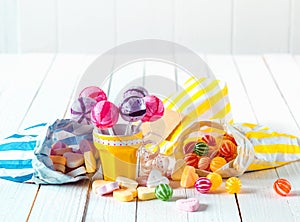 Assortment of candies in bags and cup over a table photo