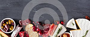 Assortment of cheese and meat appetizers, bottom border on a slate stone banner background