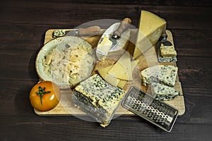 Assortment of cheeses still life with knives, tomato, blue cheese,