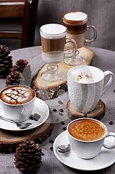 Assortment of coffee Cafe Latte, Caramel Latte, Americano, Macchiato, Espresso, Cappuccino served in cup isolated on table side photo