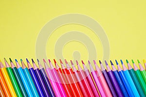 Assortment of colored pencils in various iridescent colors on a yellow