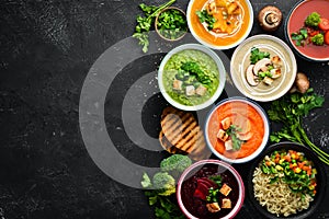 Assortment of colored vegetable cream soups. Dietary food. On a black stone background. Top view. photo