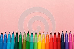 Assortment of colorful felt tip pens on pastel pink background