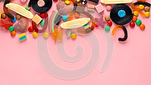 Assortment of colourful lollipops and candies on pink like background,  copy space, panorama