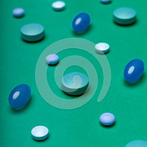 Assortment of colourful pills on green coloured background. Medication and prescription pills background.