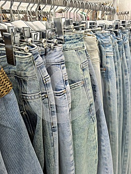 An assortment of denim pants hanging on a rack in a clothing store. photo