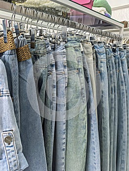 An assortment of denim pants hanging on a rack in a clothing store. photo