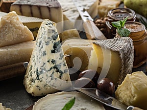 Assortment of different cheeses with olives and jams. Food background