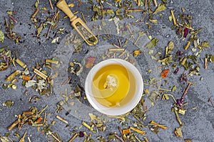 Assortment of different grade dry tealeaf in wooden spoons and two cup of green tea. Organic herbal, green and black tea with dry photo