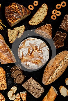 Assortment of different types of bread on a black background. Top view