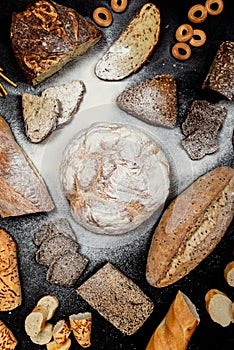 Assortment of different types of bread on a black background. Top view