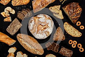 Assortment of different types of bread on a black background. Top view