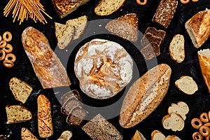 Assortment of different types of bread on a black background. Top view