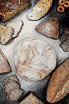 Assortment of different types of bread on a black background. Top view