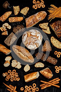 Assortment of different types of bread on a black background. Top view