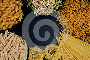Assortment of different types of pasta dry on black background