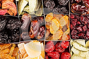 Assortment of dried fruits closeup background in square cells.