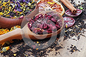 Assortment of dry tea. different varieties of tea on a wooden table. blended tea with flower petals, hibiscus in a wooden spoon an
