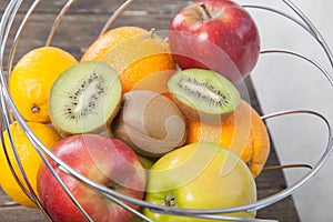 Assortment of exotic fruits close-up: kiwi, red and green apple, oranges and lemon on wooden table.