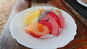 Assortment of exotic ripe and juicy fruit slices of pineapple, dragon fruit, yellow mango, watermelon, served on a white