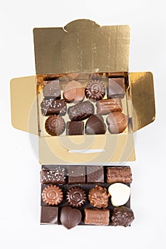 Assortment of fine chocolates candies in small golden open gift gold box of dark milk chocolate