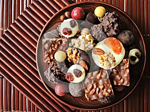 Assortment of fine chocolates in white, dark and milk chocolate on wooden background