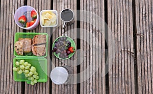 assortment of food items on weathered wooden surface. concepts: family picnic, healthy eating choices, outdoor dining